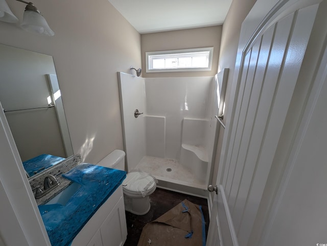 bathroom with toilet, vanity, and a walk in shower