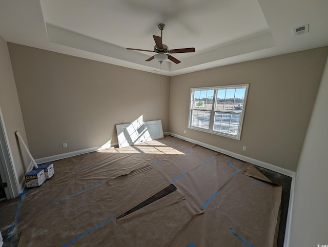 spare room with a tray ceiling, baseboards, and visible vents