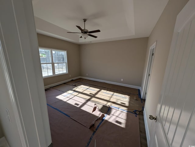 empty room with a raised ceiling and ceiling fan