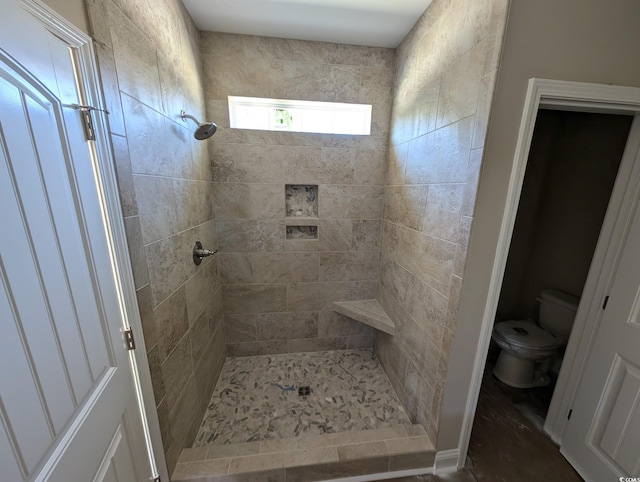 bathroom featuring a tile shower and toilet