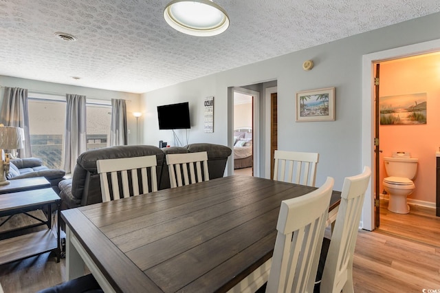 dining room with light hardwood / wood-style flooring and a textured ceiling