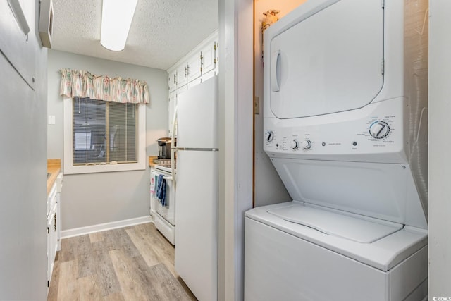 laundry room featuring stacked washer / dryer, a textured ceiling, and light wood-type flooring