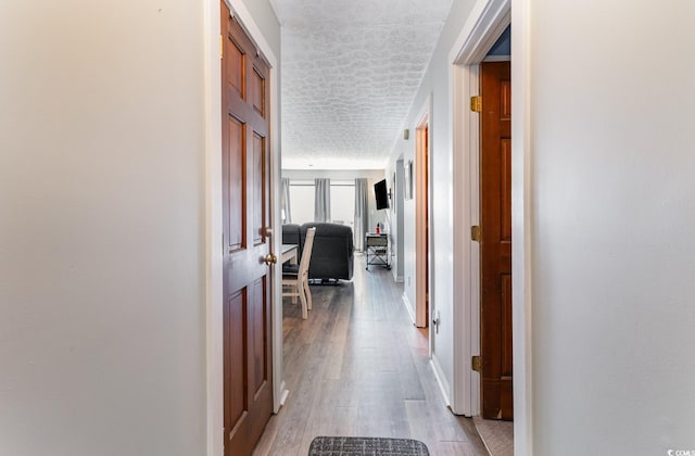 corridor featuring hardwood / wood-style flooring and a textured ceiling