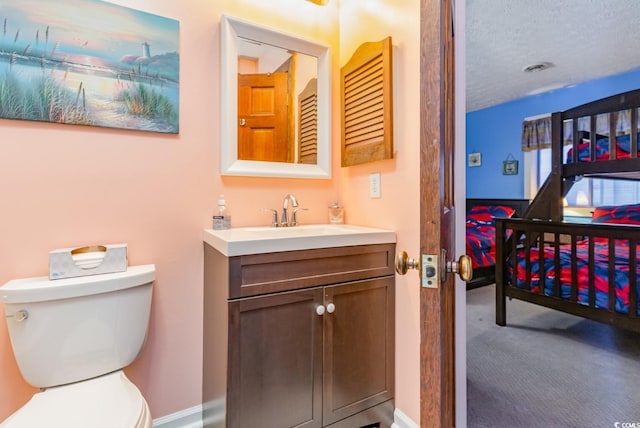 bathroom with vanity, toilet, and a textured ceiling