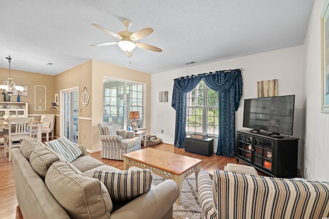 living room featuring ceiling fan with notable chandelier, a textured ceiling, and hardwood / wood-style floors