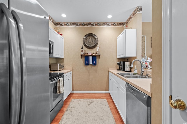 kitchen with light hardwood / wood-style flooring, sink, stainless steel appliances, and white cabinetry