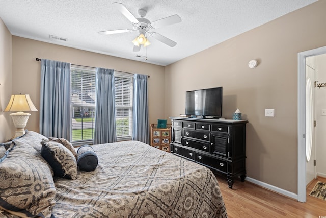 bedroom with light hardwood / wood-style flooring, ceiling fan, and a textured ceiling