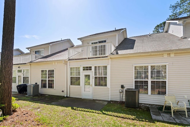 rear view of house featuring central AC, a balcony, and a lawn