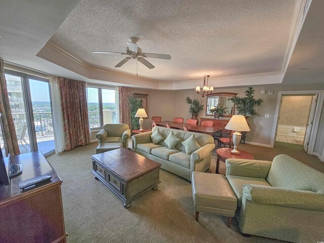 carpeted living room featuring ceiling fan with notable chandelier, a raised ceiling, and ornamental molding