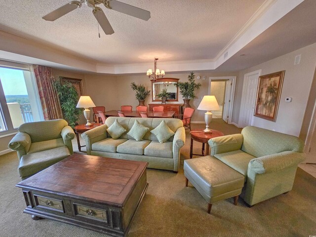 living room featuring ceiling fan with notable chandelier, a textured ceiling, carpet flooring, a raised ceiling, and ornamental molding