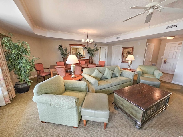 carpeted living room with ornamental molding, ceiling fan with notable chandelier, and a raised ceiling