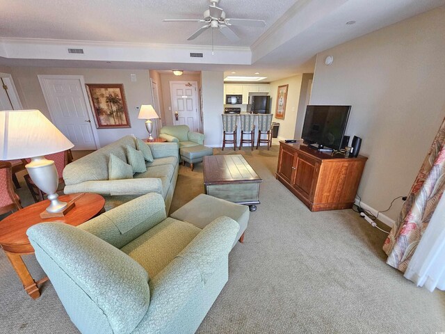 living room featuring ceiling fan, carpet flooring, and a raised ceiling