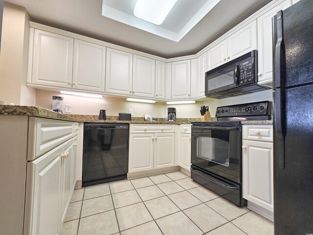 kitchen with white cabinets, light tile floors, black appliances, and a tray ceiling