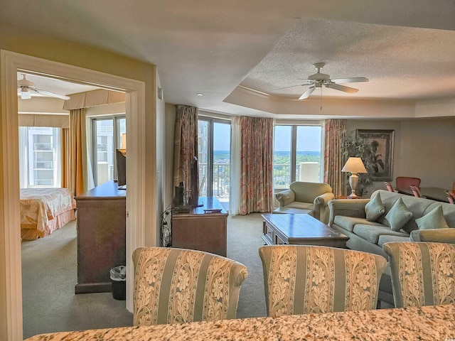 living room featuring ceiling fan, dark carpet, a tray ceiling, and a textured ceiling