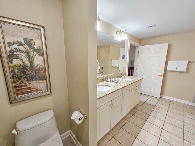 bathroom with tile flooring, double sink vanity, and toilet