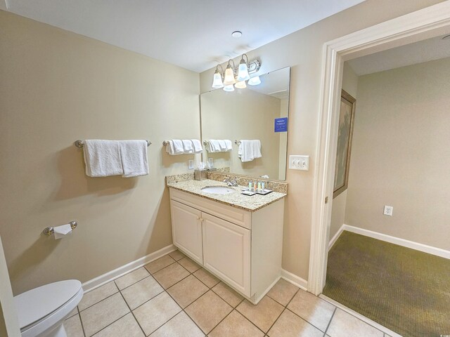 bathroom featuring toilet, vanity with extensive cabinet space, and tile flooring