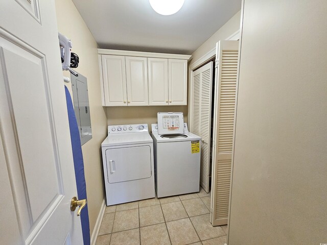 laundry room with light tile flooring, cabinets, and washing machine and clothes dryer