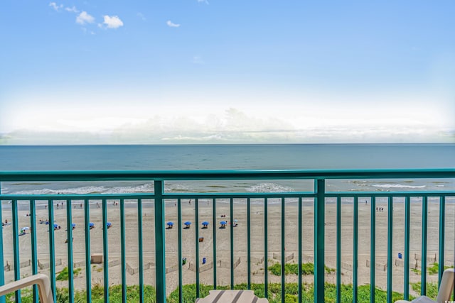 balcony with a water view and a view of the beach