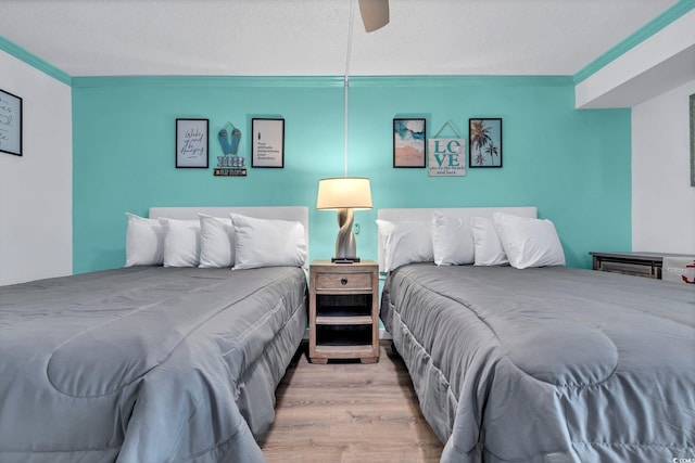 bedroom with a textured ceiling, hardwood / wood-style floors, ceiling fan, and crown molding