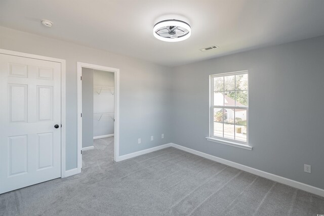 unfurnished bedroom featuring carpet, a closet, and a walk in closet