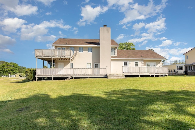 rear view of property with a deck, a yard, and a balcony