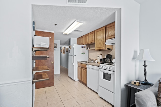 kitchen with decorative backsplash, extractor fan, a textured ceiling, light tile patterned flooring, and white appliances