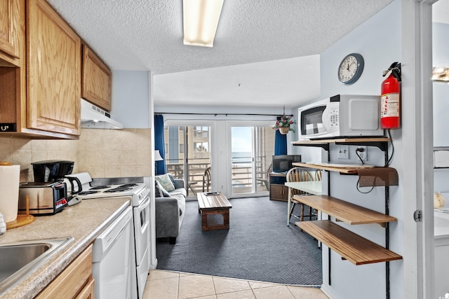 kitchen featuring sink, a textured ceiling, white appliances, and light tile patterned floors