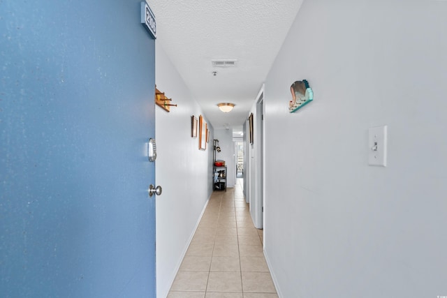 hallway with light tile patterned flooring and a textured ceiling