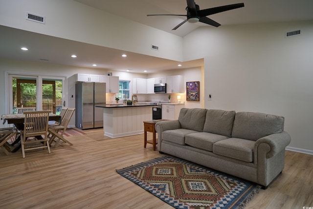 living room with ceiling fan, high vaulted ceiling, and light hardwood / wood-style flooring