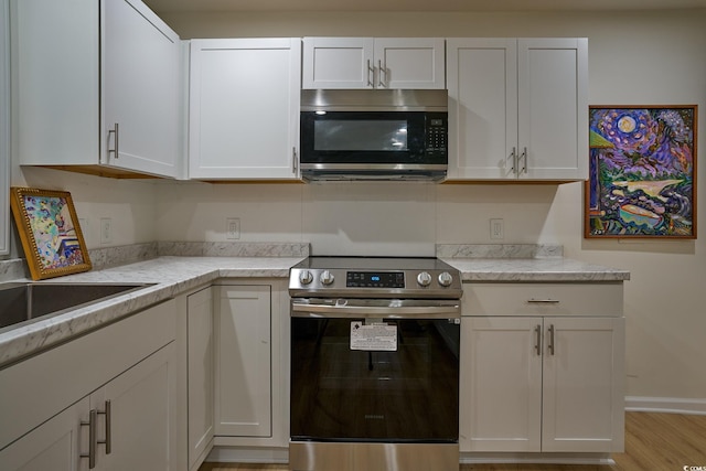 kitchen featuring light hardwood / wood-style floors, appliances with stainless steel finishes, and white cabinetry