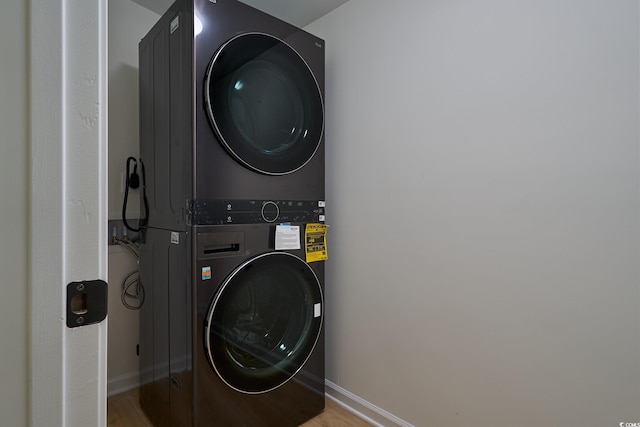 laundry area featuring stacked washer / drying machine and wood-type flooring