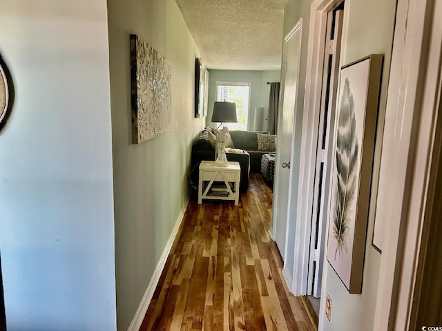 hallway with hardwood / wood-style floors and a textured ceiling