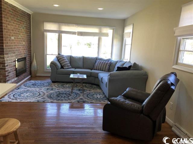 living room featuring a fireplace, dark hardwood / wood-style floors, and baseboard heating