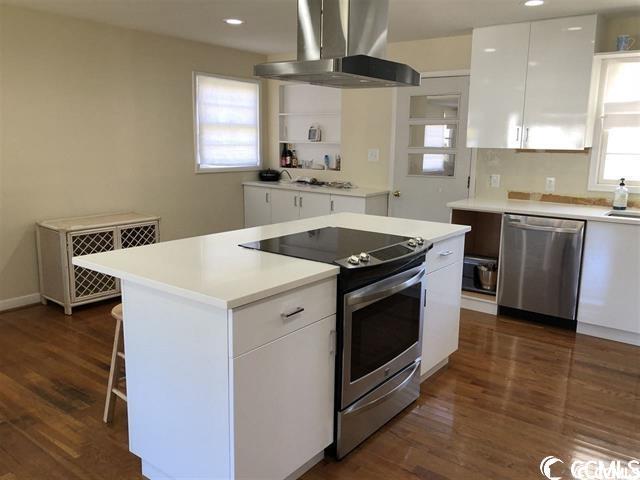 kitchen featuring a healthy amount of sunlight, extractor fan, stainless steel appliances, and white cabinets