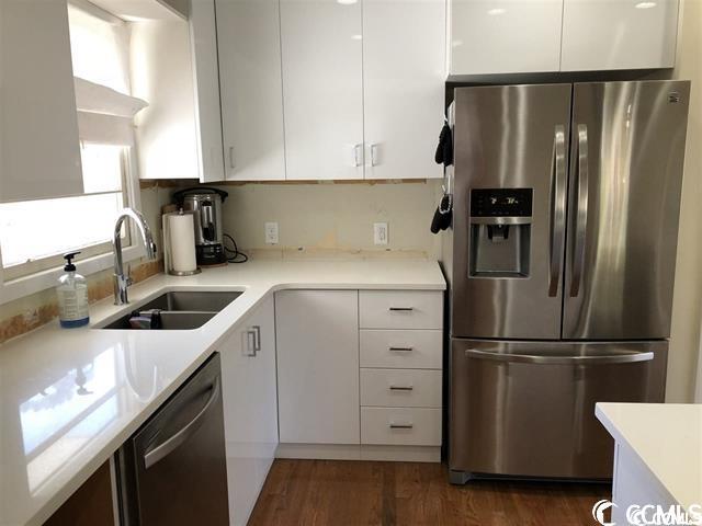 kitchen featuring sink, dark hardwood / wood-style flooring, stainless steel appliances, and white cabinets