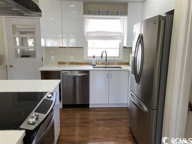 kitchen with dark hardwood / wood-style floors, sink, range hood, white cabinetry, and appliances with stainless steel finishes