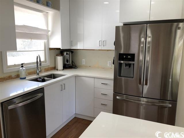 kitchen featuring dark hardwood / wood-style flooring, stainless steel appliances, white cabinets, and sink