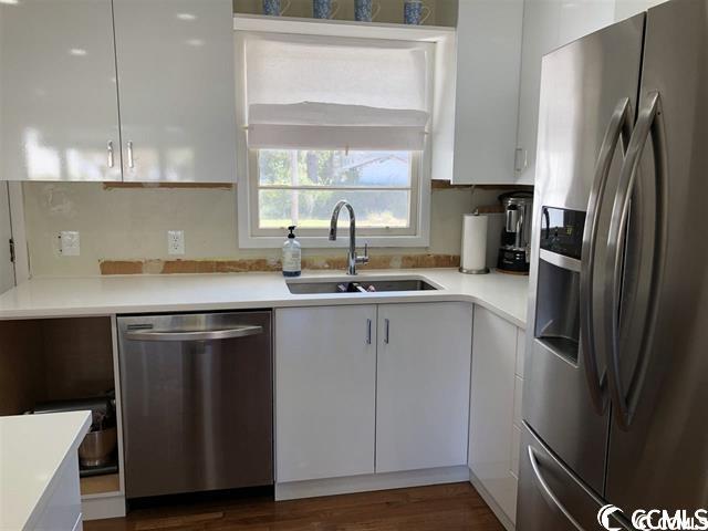 kitchen with stainless steel appliances, white cabinets, and sink