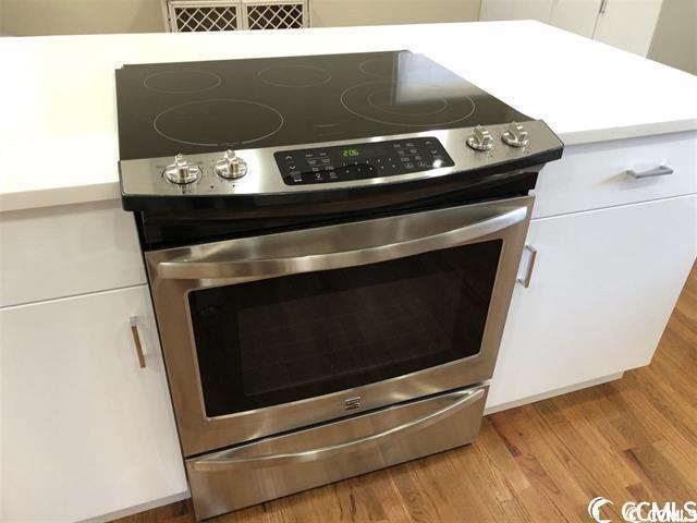 room details featuring stainless steel range with electric stovetop, light wood-type flooring, and white cabinetry