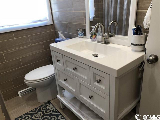 bathroom featuring vanity, tile walls, tile patterned flooring, and toilet