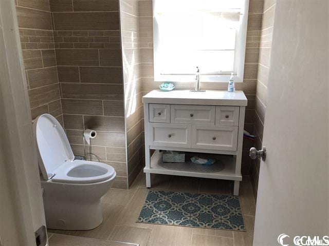 bathroom with vanity, tile walls, tile patterned flooring, and toilet