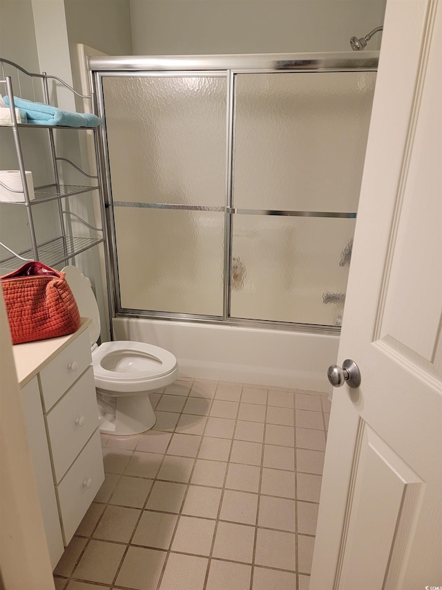 full bathroom with toilet, tile flooring, vanity, and shower / bath combination with glass door