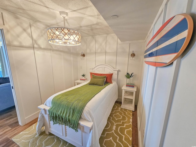 bedroom featuring wood finished floors and a decorative wall