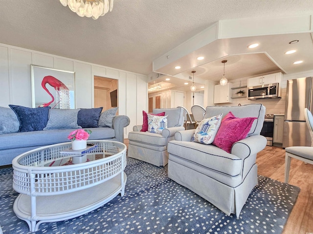 living room featuring a textured ceiling, light wood-type flooring, and recessed lighting