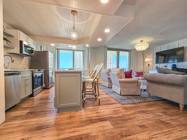 kitchen featuring appliances with stainless steel finishes, open floor plan, a sink, a kitchen island, and light wood-type flooring