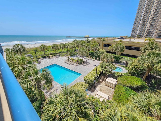 pool featuring a water view, a patio area, and a view of the beach