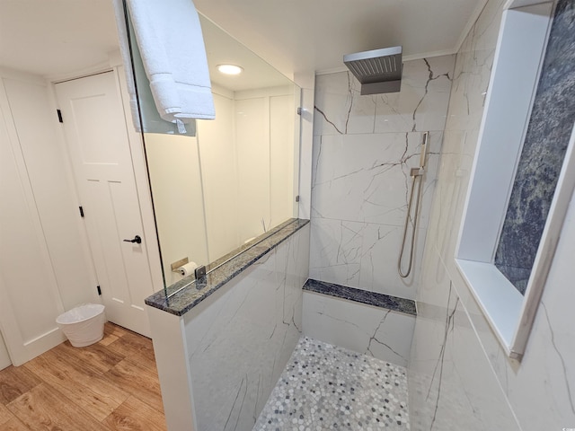 full bath with a marble finish shower and wood finished floors