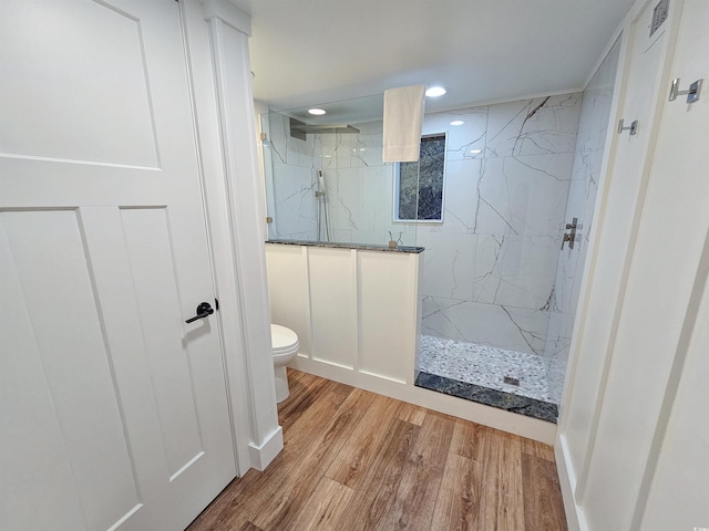 bathroom with recessed lighting, a marble finish shower, toilet, and wood finished floors