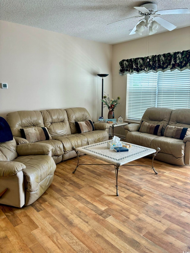 living room with a textured ceiling, hardwood / wood-style floors, and ceiling fan