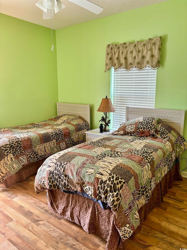 bedroom with wood-type flooring, a textured ceiling, and ceiling fan